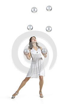 A young female circus performer, juggles silver balls.