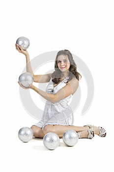 A young female circus performer, juggles silver balls.