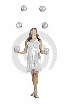 A young female circus performer, juggles silver balls.