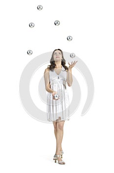 A young female circus performer, juggles silver balls.