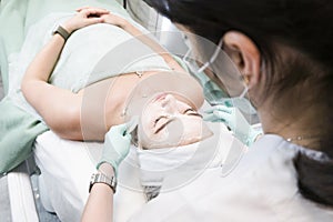 The young female client of cosmetic salon having a cleansing facial mask. The procedure of applying a peeling mask to the face