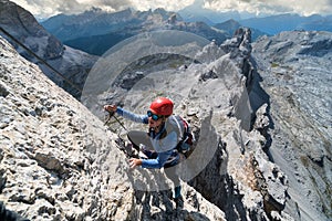 Young female climber on an exposed Via Ferrata in South Tyrol