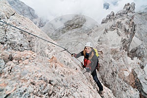 Young female climber on a steep and exposed rock face climbing a Via Ferrata