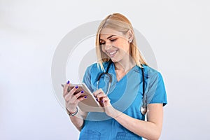 Young female clinician doctor in scrubs using touchpad while communicating with patients online. Portrait Of Smiling Female Doctor