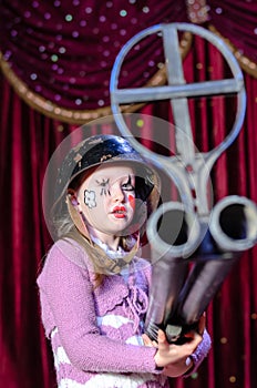 Young Female Clown in Helmet Aiming Large Rifle