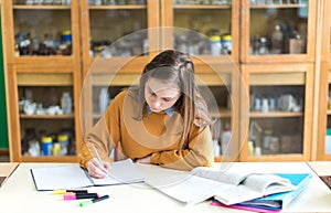 Young female college student in chemistry class, writing notes. Focused student in classroom.