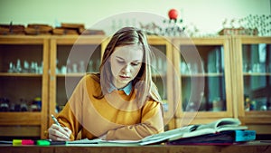 Young female college student in chemistry class, writing notes. Focused student in classroom. Authentic Education concept.