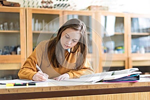 Young female college student in chemistry class, writing notes. Focused student in classroom.