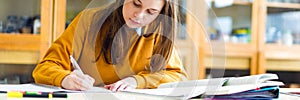 Young female college student in chemistry class, writing notes. Focused student in classroom.