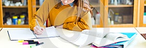 Young female college student in chemistry class, writing notes. Focused student in classroom.