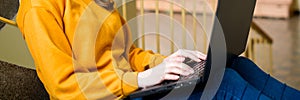 Young female college student sitting on stairs at school, writing essay on her laptop. Education. photo