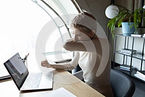 Young female company employee coughing sneezing in elbow.