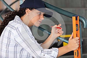 young female construction worker checking level wall