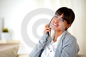 Young female conversing on phone looking at you