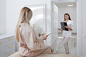 Young female cosmetologist confidently enters treatment room with waiting patient