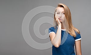 Young female covers face hand, feels fatigue. Weariness and people. Studio shot, gray background. Copy space