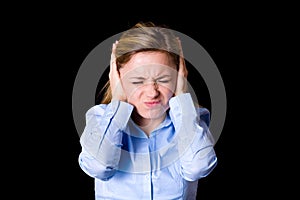 Young female covers her ears from noise, emotions