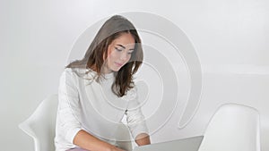 Young female creating something using laptop while working remotely indoors, woman typing email during working online on