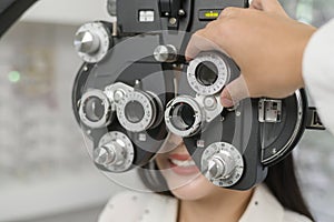 Young female customer being examined visual test using Bifocal Optometry eyesight measurement device by ophthalmologist in optical photo
