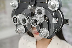 Young female customer being examined visual test using Bifocal Optometry eyesight measurement device by ophthalmologist in optical photo