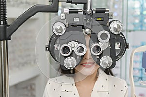 Young female customer being examined visual test using Bifocal Optometry eyesight measurement device by ophthalmologist in optical photo