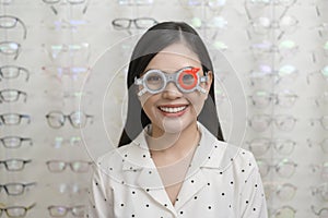 Young female customer being examined visual test using Bifocal Optometry eyesight measurement device by ophthalmologist in optical photo