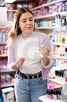 Young female customer searching for reliable lipstick in cosmetics shop