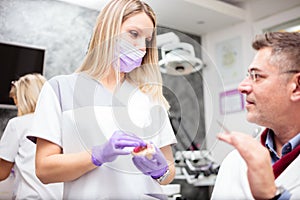 Young female dental technician consulting with a mature male doctor in dental clinic