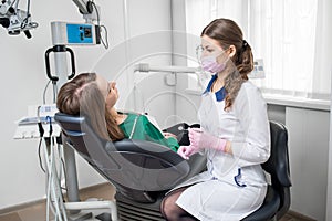 Young female dentist with beautiful woman patient before dental procedure in modern dental office. Dentistry