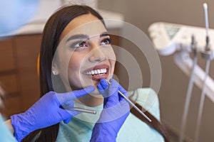 Young female dentist curing patient`s teeth filling cavity. Stomatologist working with professional equipment in clinic office.
