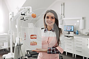 Young female dentist showing picture of teeth in her office