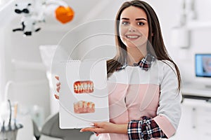 Young female dentist showing picture of teeth in her office