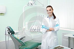 Young female dentist in white coat at workplace