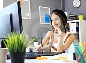 Young female designer using graphics tablet while working