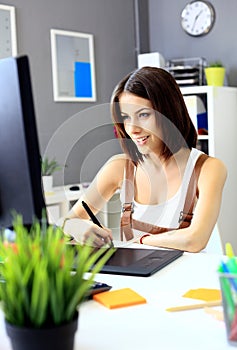 Young female designer using graphics tablet while working