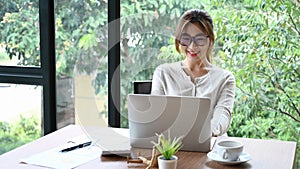 Young female designer working with computer laptop in modern office room.