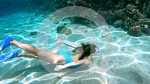 Young female diver in the blue swimsuit dive at the crystal blue ocean's water.