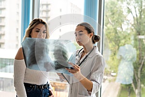 Young female doctor is analyzing x-ray images of the patient lung and consulting for quick recovery