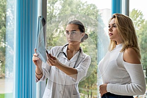 Young female doctor is analyzing x-ray images of the patient lung and consulting for quick recovery