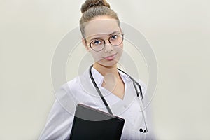 A young female doctor with confidence and care looks directly at the camera with a laptop in her hands