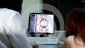 Young female doctor examines tomography magnetic resonance imaging mri scan of stuffed plush bear body organs kid toy