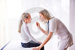 Young female doctor examining a small girl in her office.