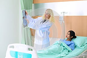 Young female doctor explained reviewing the x-ray report to patient sitting in hospital bed. Medical examination for infections,