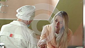 Young female doctor with female patient talking in hospital room