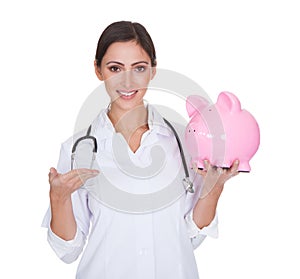 Young female doctor holding piggy bank