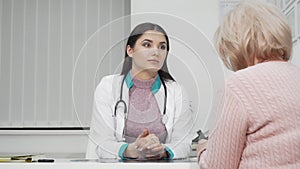 Young female doctor listening to her senior patient during medical appointment