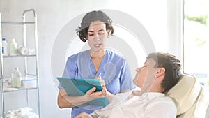 Young female doctor and male patient talking before signing of medical contract