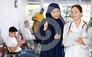 Young female doctor showing papers to asian female patient