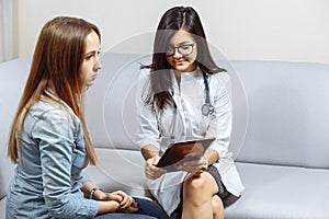 Young female doctor showing patient test results on digital tablet