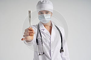 Young female doctor showing thermometer over white background, studio shot